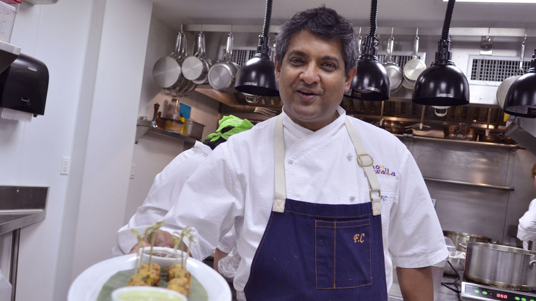 Floyd Cardoz holding a plate of food in a kitchen