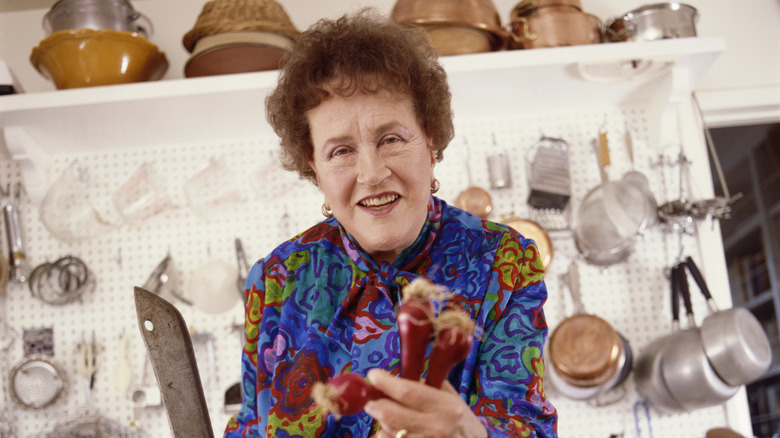 Julia Child holding items in a kitchen