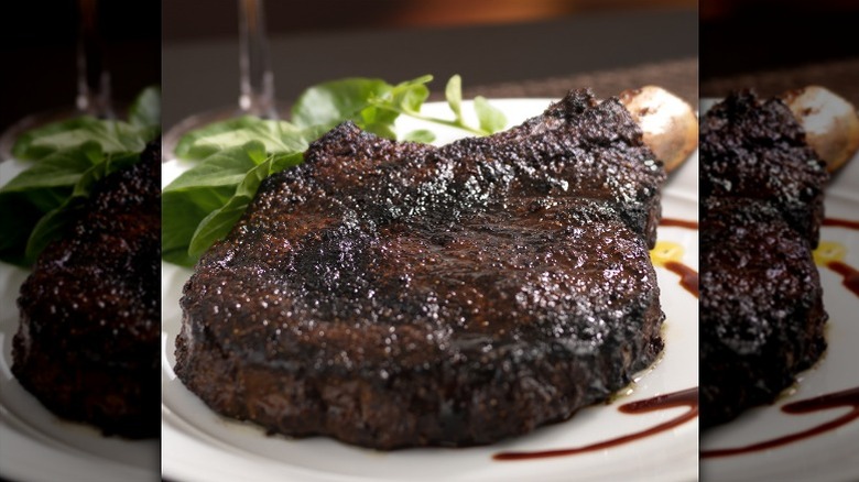 seared bone-in ribeye on plate with balsamic glaze and fresh spinach