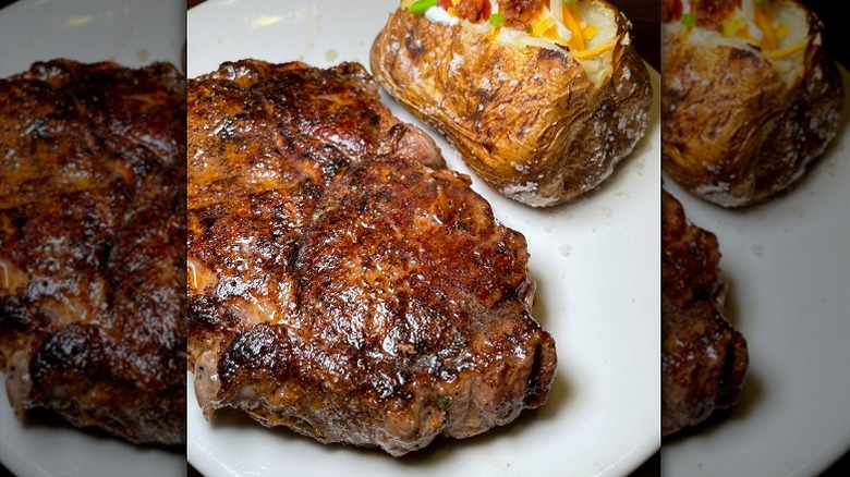 seared boneless ribeye with loaded backed potato on white plate
