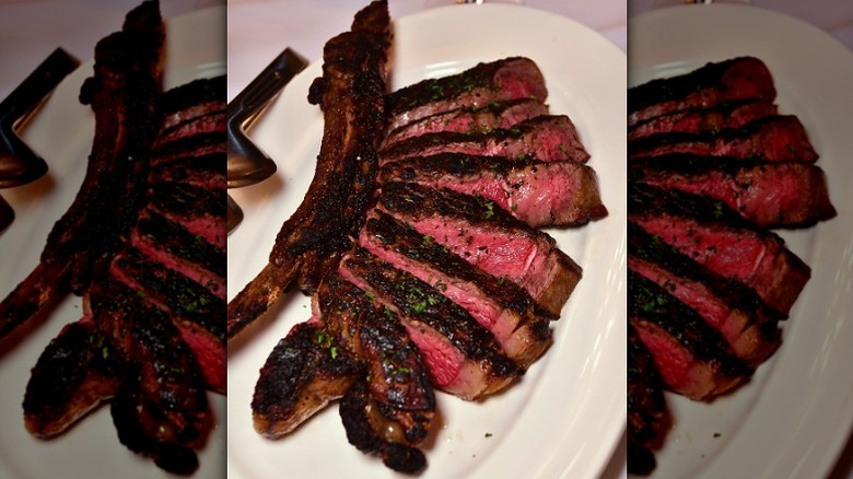 seared and sliced ribeye with bone on white plate