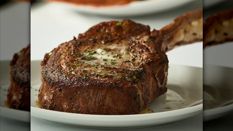 seared tomahawk ribeye topped with melted butter on plate