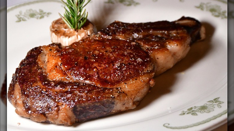 seared bone-in ribeye with herbs on decorative plate