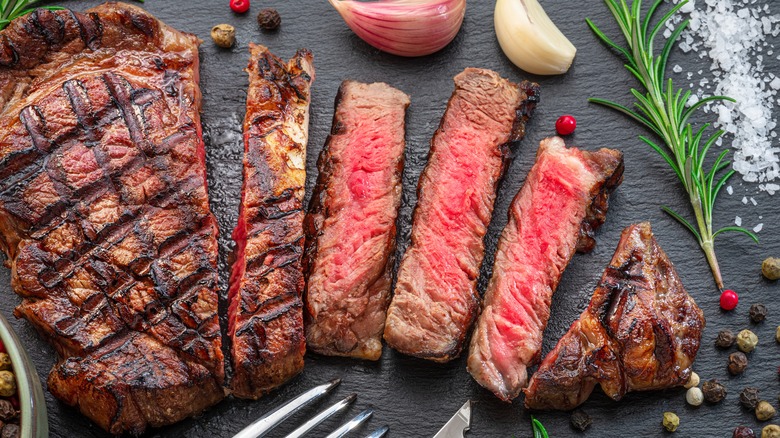 grilled ribeye sliced on board with herbs