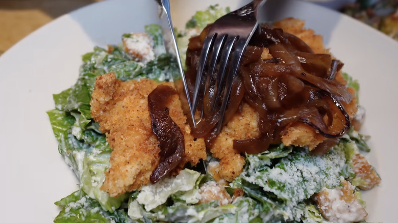 Knife cutting into the chicken of a Louisiana Chicken Caesar Salad