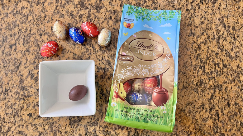 Lindt Egg Chocolate Bag on countertop with a few wrapped eggs on a counter and one unwrapped in a dish