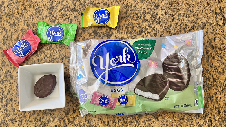 Unwrapped York Dark Chocolate Peppermint Egg in a dish next to three wrapped eggs and a wrapper