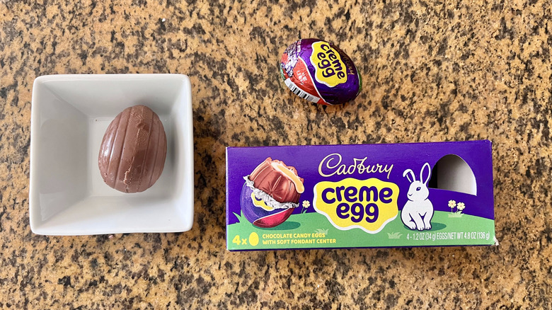 Cadbury Crème Egg Chocolate wrapper on countertop with one wrapped egg on the counter and one unwrapped in the dish
