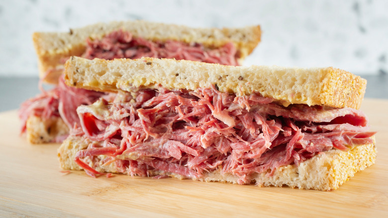 Corned beef sandwich cut in half on a wooden board