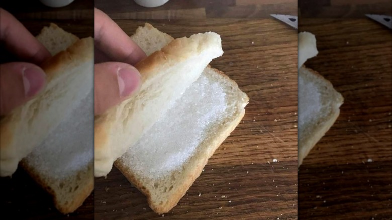 Close-up of a hand opening up a sugar sandwich on a wooden table