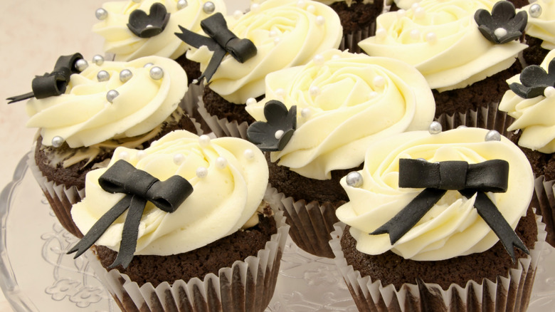 cupcakes decorated with white frosting and black non-edible bows