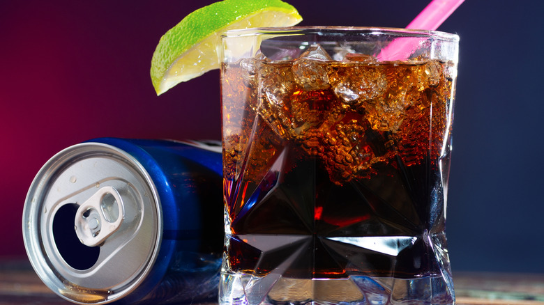 Close-up of whiskey and cola in rocks glass with lime and Pepsi can.