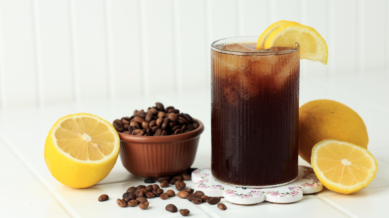 Coffee with Tonic in a Tall Glass with Ice and Lemon on White Table Background.