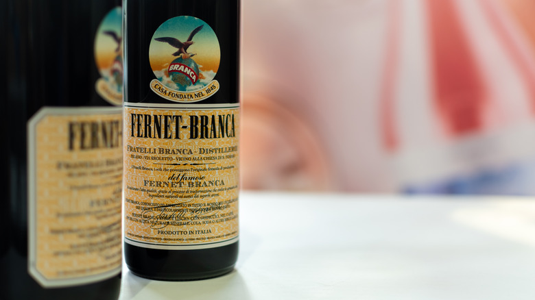 Close up and side view of two bottles of Fernet with out of focus background.