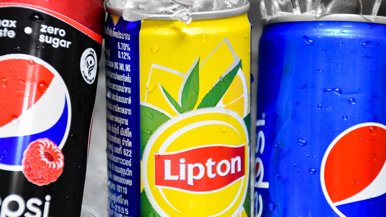 A close-up of cans of Pepsi, Lipton Iced Tea, and flavored Pepsi.