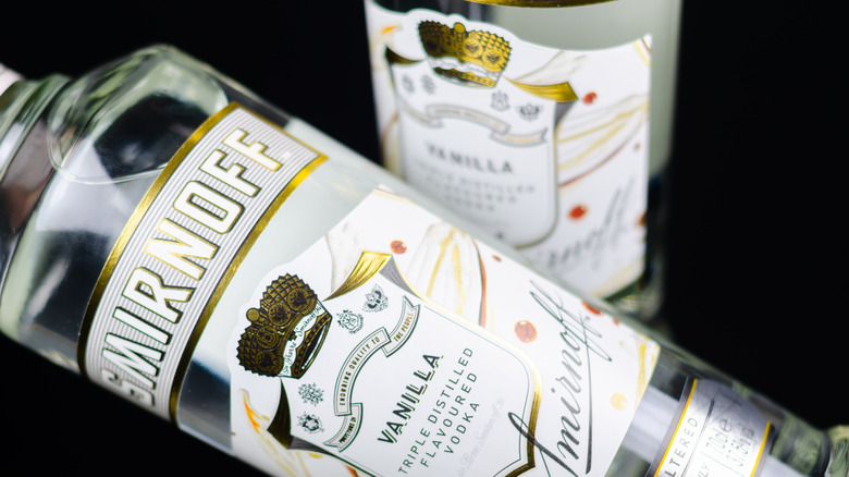 A close up of two bottles of Smirnoff vanilla vodka against black background.