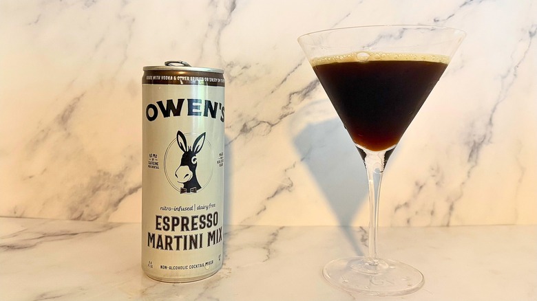 Can of Owen's espresso martini mix next to espresso martini in glass on marble surface