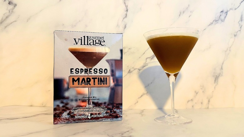 Box of Gourmet du Village espresso martini mix next to espresso martini in glass on marble surface