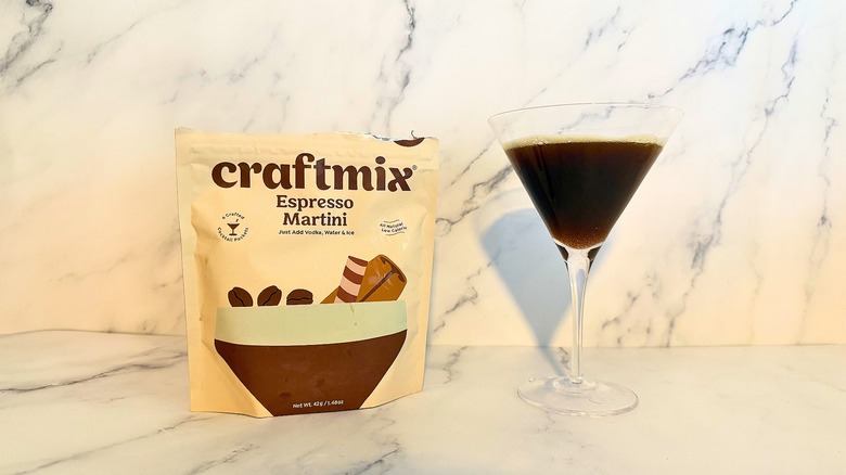 Box of Craftmix espresso martini mix next to espresso martini in glass on marble surface
