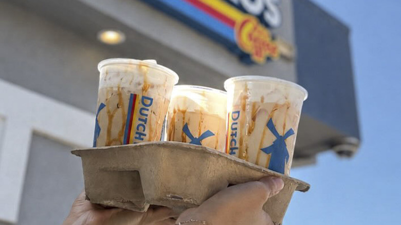 3 Dutch Bros Cookie Butter Latte coffees being held up in a cardboard holder