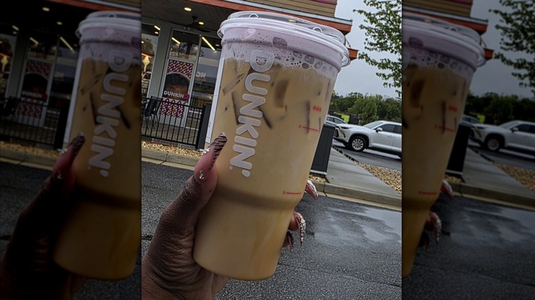Hand holding iced Dunkin' coffee with purple cold foam
