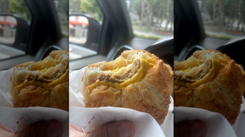 Hand holding Dunkin' breakfast sandwich in car