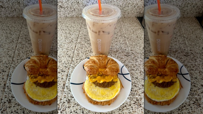 Dunkin' sandwich with egg on plate next to drink