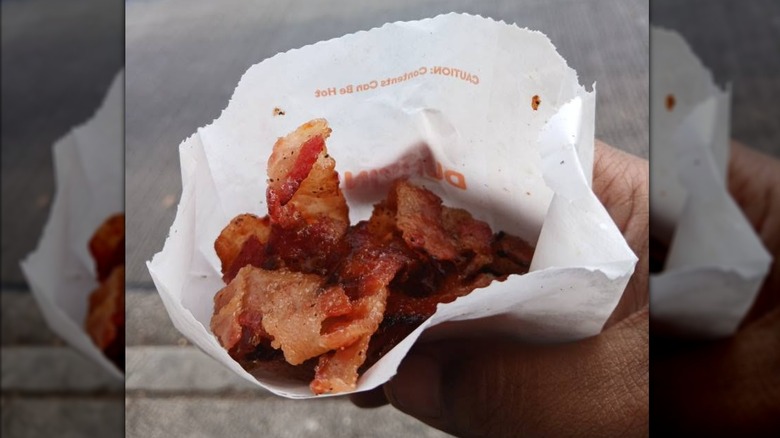 Hand holding paper bag of Dunkin' Snackin' Bacon