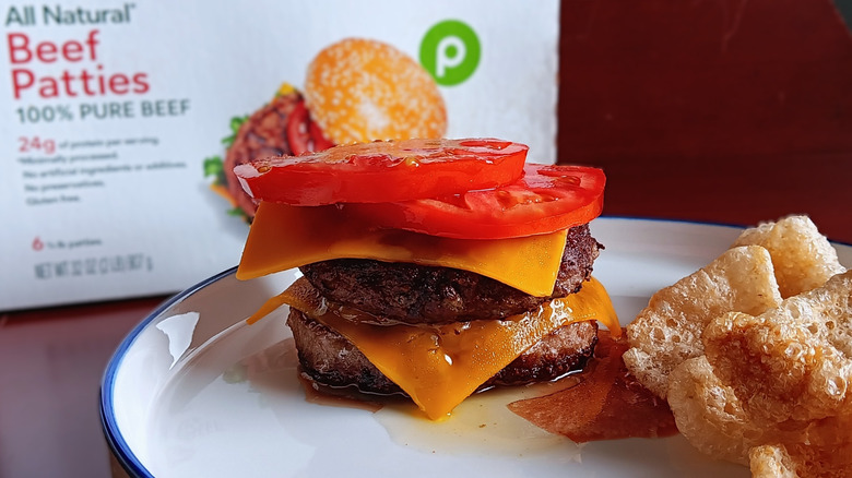 Double cheeseburger with tomatoes in front of Publix frozen beef patties box