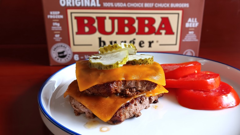 double cheeseburger with pickles and a side of tomato slices on white plate in front of Bubba frozen beef burgers box