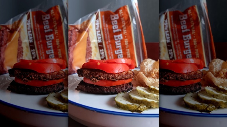 double burger with tomatoes, side of pickles on plate with Aldi beef burgers bag in back