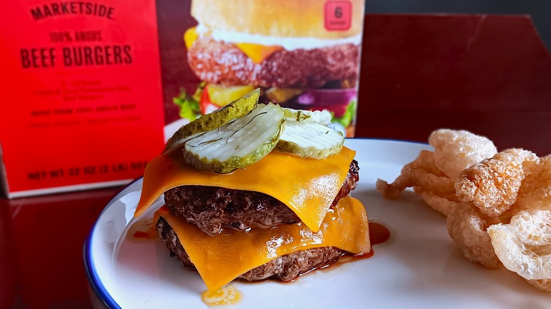 Double cheeseburger with pickles on white plate in front of Marketside frozen beef burgers box