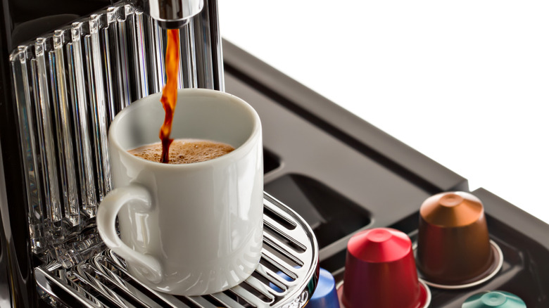 Single-serve coffee maker brewing into mug with coffee pods on the side