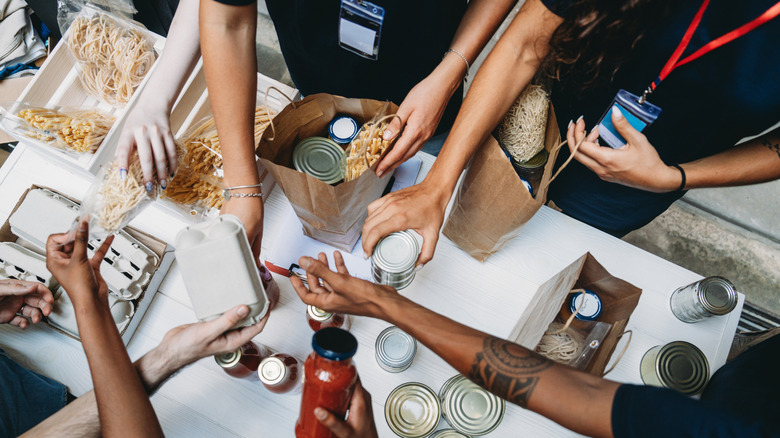 the hands of volunteers distributing donated food at a food bank