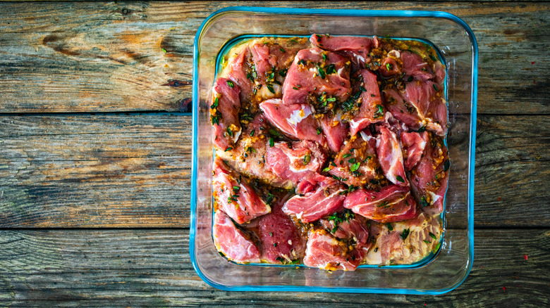 Raw seasoned meat in glass dish with liquid in the bottom