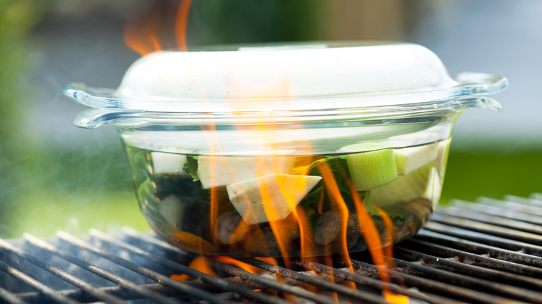 Glass dish on grill with soup inside