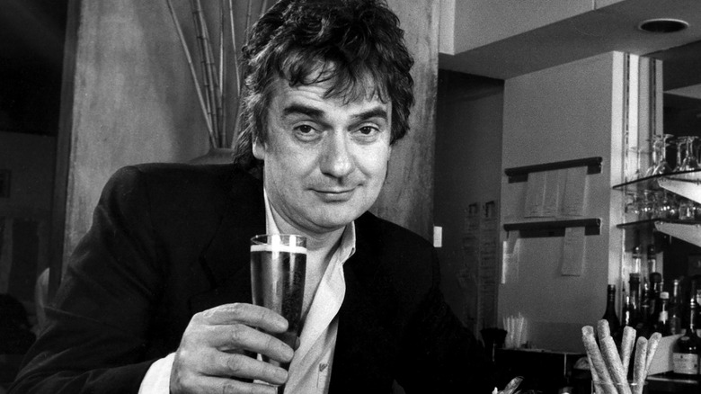 black and white image of Dudley Moore sitting at a bar with a drink