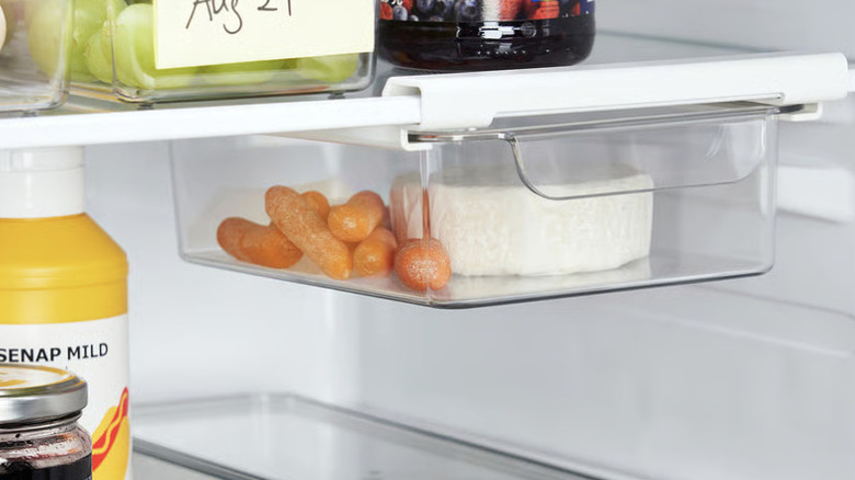 Attachable clear drawer for the refrigerator filled with cheese and baby carrots