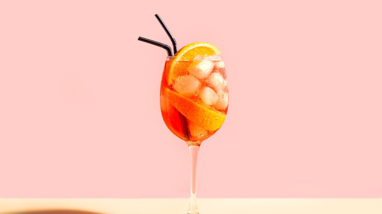 Aperol Spritz cocktail with orange slices, ice, and black straws