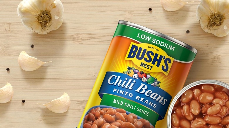 Can of Bush's Low Sodium Chili Pinto Beans surrounded by heads of garlic