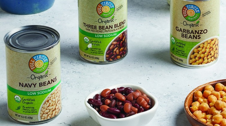 Three cans of beans from Full Circle Market surrounded by bowls of beans