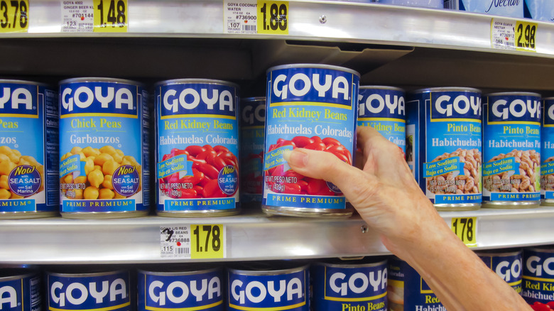 Selecting can of low-sodium Goya beans from supermarket shelf