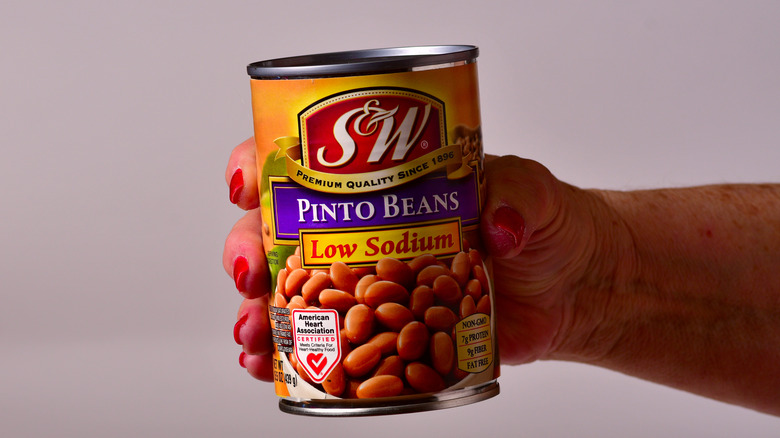Female hand showing can of low-sodium S&W pinto beans