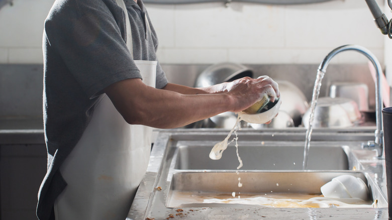 Man washing dishes in a kitchen sink