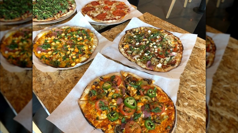 Three Indian pizzas with an assortment of toppings on parchment paper