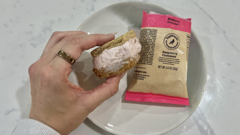 Hand holding chomps size Raspberry Croissant Nightingale ice cream sandwich.