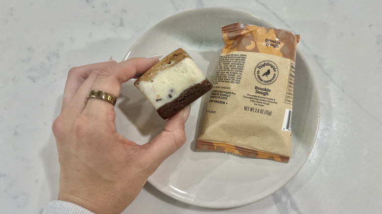 Hand holding chomps size Brookie Dough Nightingale ice cream sandwich.