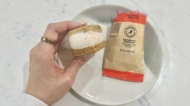 Hand holding chomps size Strawberry Shortcake Nightingale ice cream sandwich.