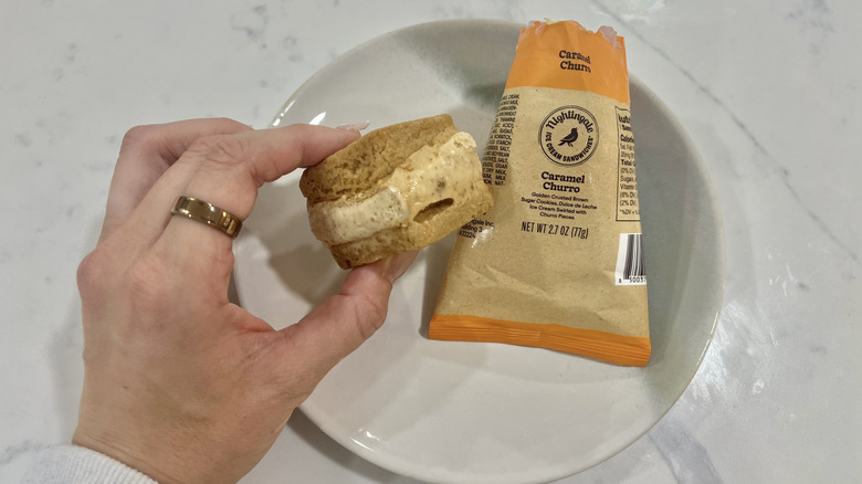 Hand holding chomps size Caramel Churro Nightingale ice cream sandwich.