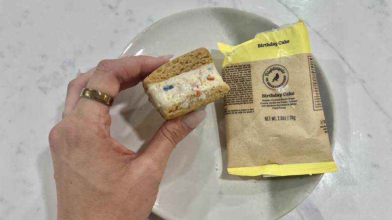 Hand holding chomps size Birthday Cake Nightingale ice cream sandwich.